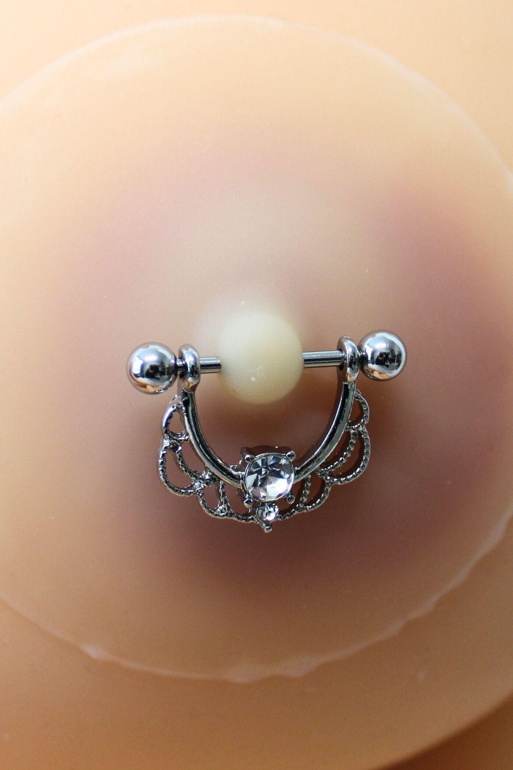Paire de cache-tétons ornés d’un piercing barre en demi-anneau avec strass, pour peau claire.
